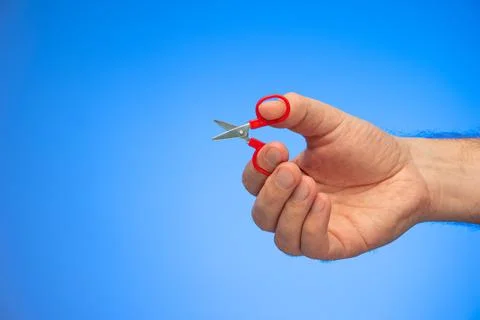 Very small scissors held in hand by Caucasian male hand studio shot isolated  Fotos de archivo