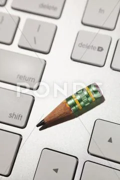 A Very Small Sharpened Lead Pencil On A Computer Keyboard