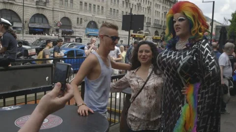 VERY TALL DRAG QUEEN GETTING PHOTOS WITH TOURISTS AT LONDON GAY PRIDE PARADE Stock Footage 130742736