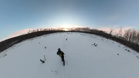 Very wide-angle view of a person snowshoeing across a snow covered marsh  Stock Footage 247638812
