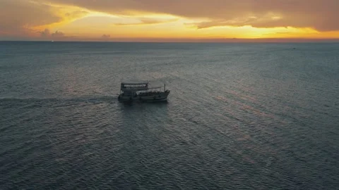 Vessel boat navigating through blue ocean under orange sunset picturesque sunset Stock Footage 312511633