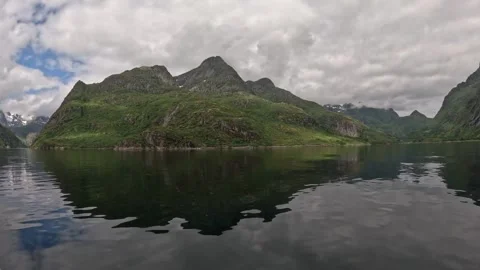 Vessel sailing past dramatic rocky cliff formations in calm fjord water Lofoten Stock Footage 344753194