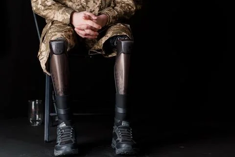 Veteran Seated with Advanced Bionic Leg Prosthesis in Military Camouflage Stock Photos