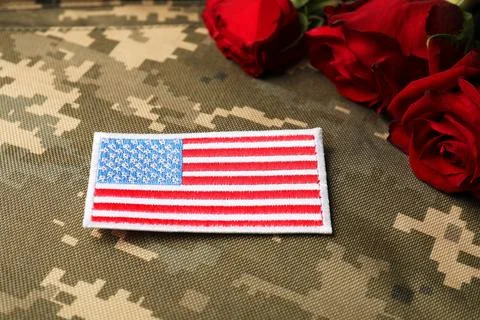 Veterans day. USA army patch and rose flowers on camouflage fabric, closeup Stock Photos