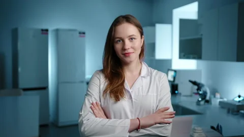 A veterinarian in a lab coat looking at the camera and crossing her arms Stock Footage 236465233