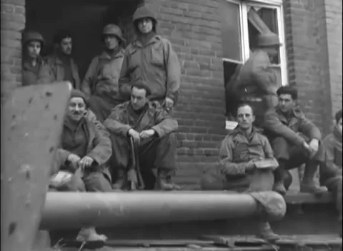 VETTWEISS, GERMANY - 1945: War aftermath - Troops rest near motionless man Stock Footage 344493123