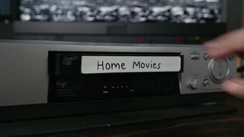 VHS Tape Inserted and Ejected from a VCR. Female Hand. Labeled "Home Movies" Stock Footage 137441418