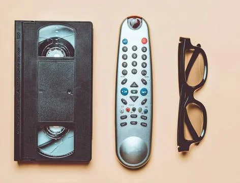 Vhs tape remote control and glasses on beige background Stock Photos