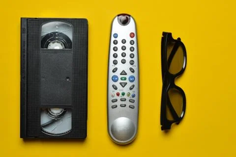 Vhs, TV remote, 3d glasses on a yellow paper background. Entertainment 90s. T Stock Photos