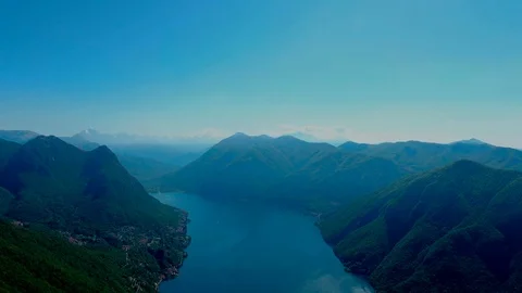 Viaggo sopra il lago verso l'infinito blu delle catene alpine Stock Footage