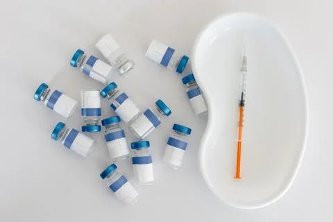 Vials and syringe on white table. Vaccination and immunization for people Stock Photos