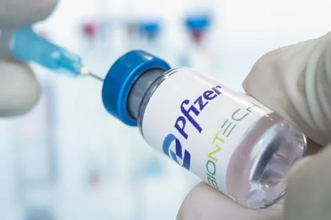 Vials of liquid the logos pfizer and biontech in the doctor's hand Stock Photos