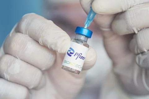 Vials of liquid the logos pfizer and biontech in the doctor's hand Stock Photos