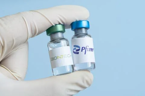 Vials of liquid the logos pfizer and biontech in the hand. Stock Photos