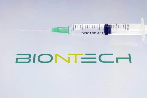 Vials of liquid on a white table and the logo of a large pharmaceutical compa Stock Photos