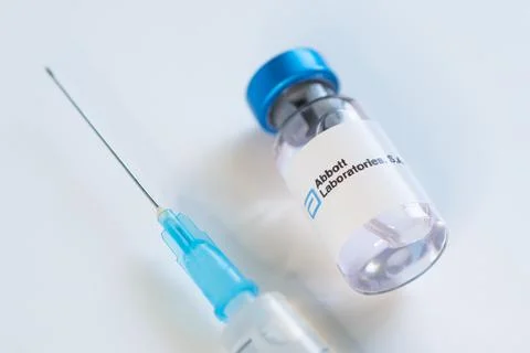 Vials of liquid on a white table and the logo of a large pharmaceutical compa Stock Photos