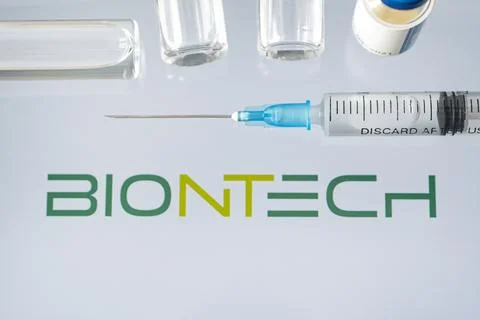 Vials of liquid on a white table and the logo biontech, large pharmaceutical  Stock Photos