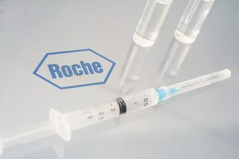 Vials of liquid on a white table and the logo of a large pharmaceutical com.. Stock Photos