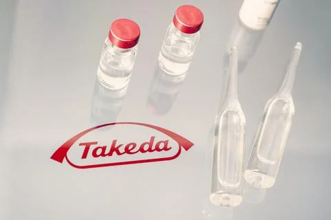 Vials of liquid on a white table and the logo of a large pharmaceutical com.. Stock Photos
