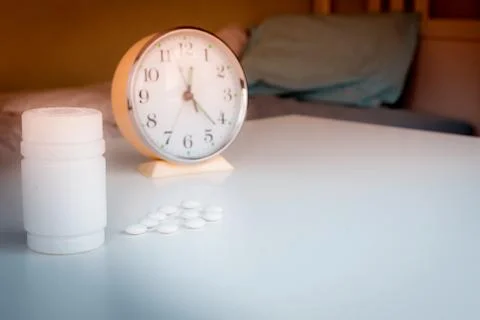 Vials of medicine on the table with the clock. time to take your medication Stock Photos