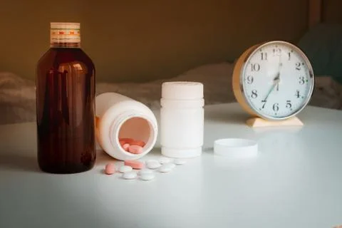 Vials of medicine on the table with the clock. time to take your medication Stock Photos