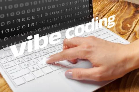 Vibe coding is happening on a laptop with a hand typing in a tech environment Foto stock