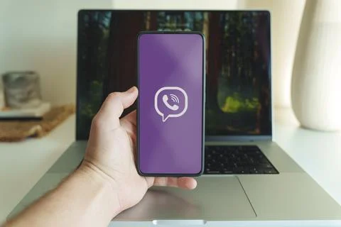 Viber messaging application logo on smartphone screen in front of laptop Stock Photos