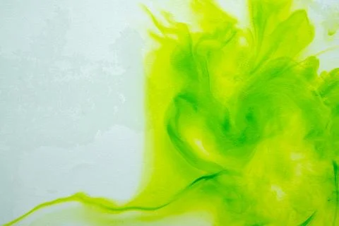 A vibrant abstract background featuring bright green and lime yellow ink or.. Stock Photos