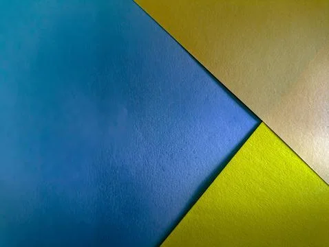 A vibrant abstract background with intersecting blue, gold, and green paper.. Stock Photos