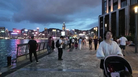 A vibrant and bustling scene at dusk on a waterfront promenade in Hong Kong, 库存影片 338280322
