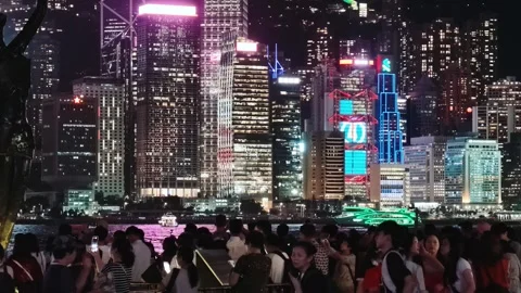 A vibrant and dynamic night scene of the Hong Kong skyline featuring the iconic 库存影片 338280383