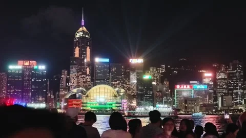 A vibrant and dynamic night scene of Hong Kong's iconic skyline viewed from a Stock Footage 338280396
