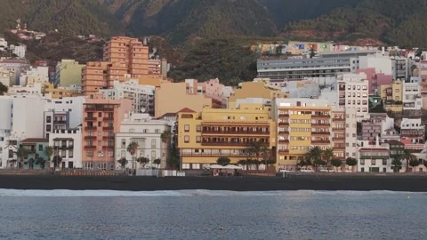 Vibrant architecture lining black volcanic shoreline, mountainous Canary Islands Stock Footage 308421441