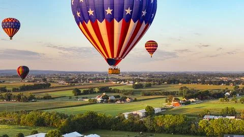Vibrant array of multicolored balloons drift high above a residential area Stock Photos