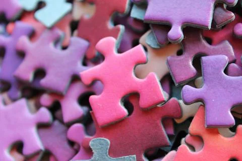 A vibrant array of puzzle pieces in shades of purple, pink, and blue set agai Stock Photos