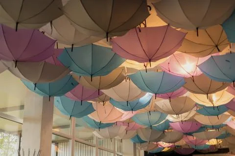 A vibrant array of umbrellas hangs from the ceiling, featuring shades of blue Stock Photos