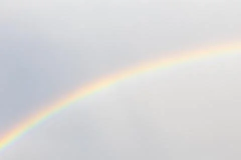 Vibrant atmospheric rainbow spectrum gradient against overcast cloudy sky Stock Photos