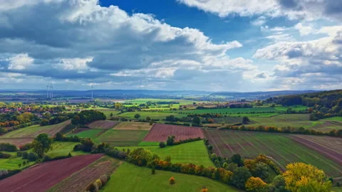Vibrant autumn landscape featuring rolling hills, patchwork fields, and dramatic Stock Footage 320825241