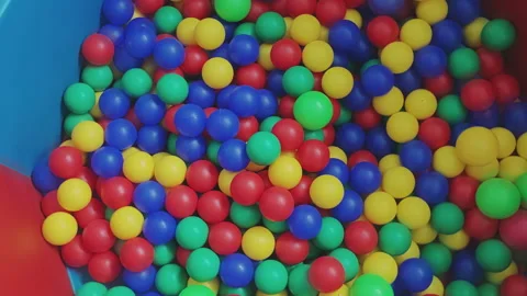 Vibrant ball pit filled with red, blue, green, and yellow plastic balls moving Stock Footage 346314877