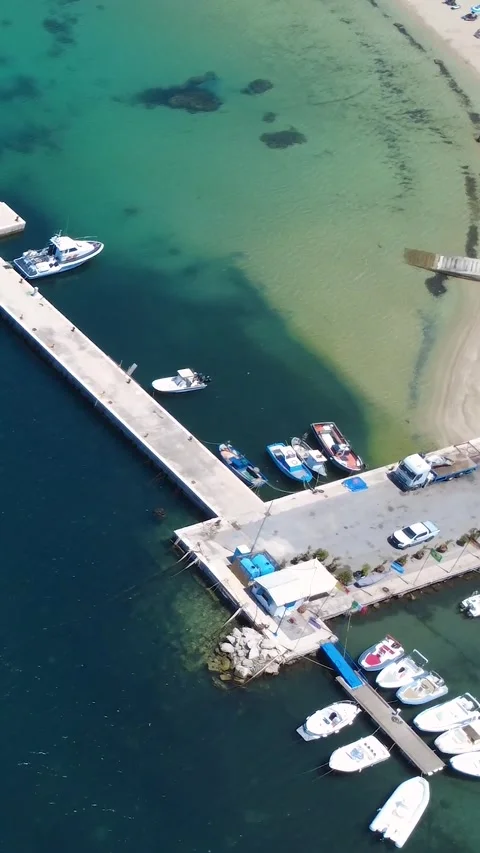 Vibrant Beach With Clear Waters and Boats Docked Under Sunny Skies in Coastal Stock Footage 311111867