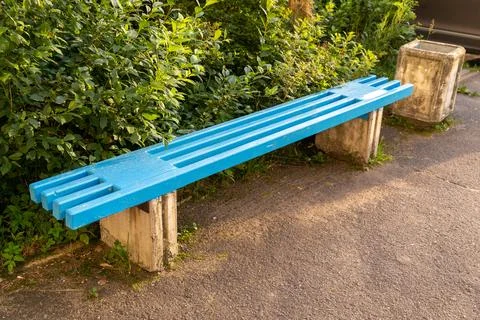 Vibrant blue bench inviting rest in a peaceful green setting Foto stock