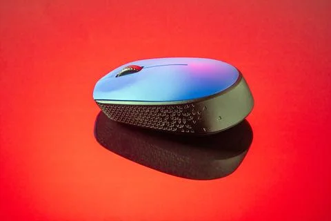 A vibrant blue computer mouse reflects on a mirrored red surface Stock Photos