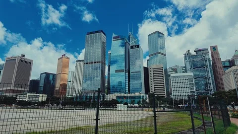 A vibrant blue sky with fluffy white clouds in front of a bustling Hong Kong Stock Footage 338311411