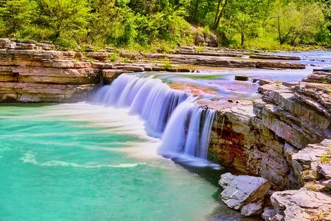 Vibrant blue waterfall in cliffs of gorge Stock-Fotos
