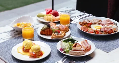Vibrant breakfast spread on outdoor table featuring eggs benedict, Видео 318118539