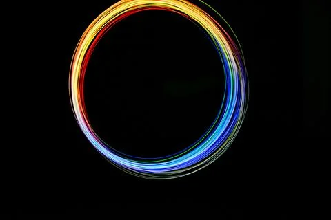 A vibrant circle of colored light forms in a dark space, showcasing movemen.. Stock Illustration