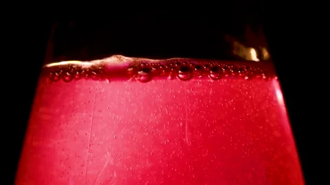 A vibrant close up of ruby red liquid in a glass against a bubbles Stockbeeldmateriaal 320419287
