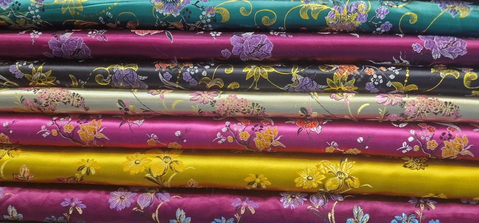 A vibrant close-up of a stack of folded silk fabrics, each with a different c 스톡 사진