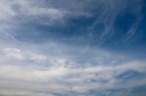 Vibrant cloud patterns dancing across a vast blue sky at midday under soft .. Stock Photos