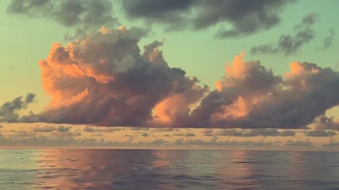 Vibrant clouds reflect warm sunlight over a calm ocean during a serene sunset Stock Footage 338281747